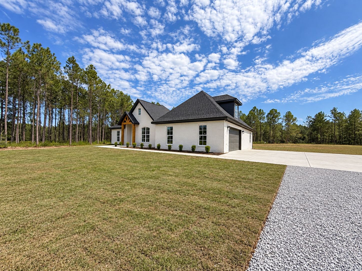 Angled exterior view of the white home, attached garage, lawn, and driveway.