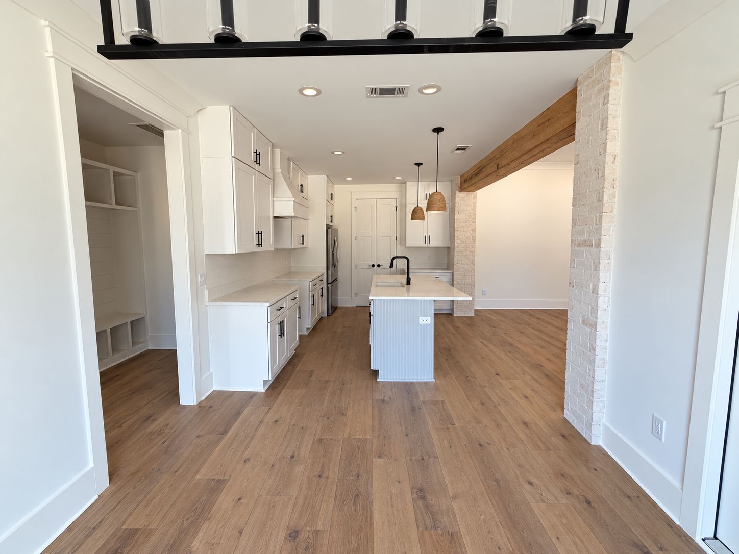 Open kitchen and living area with white cabinetry, an island, and wood-look flooring.