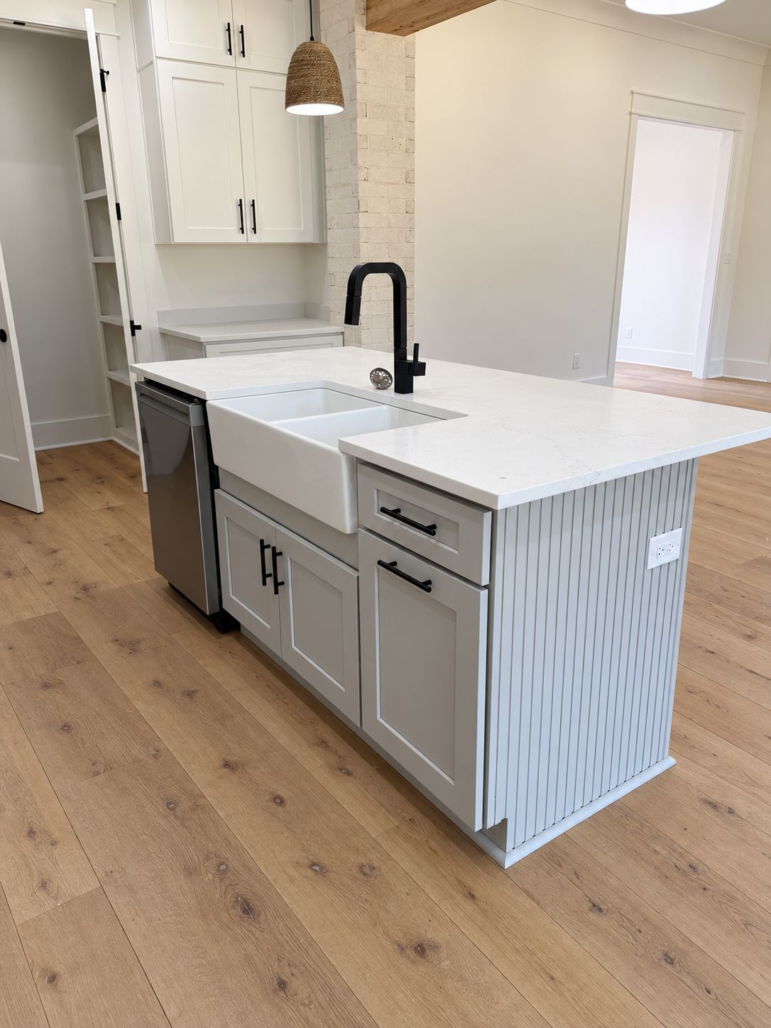 Kitchen island with a white countertop, dark faucet, and paneled gray base.