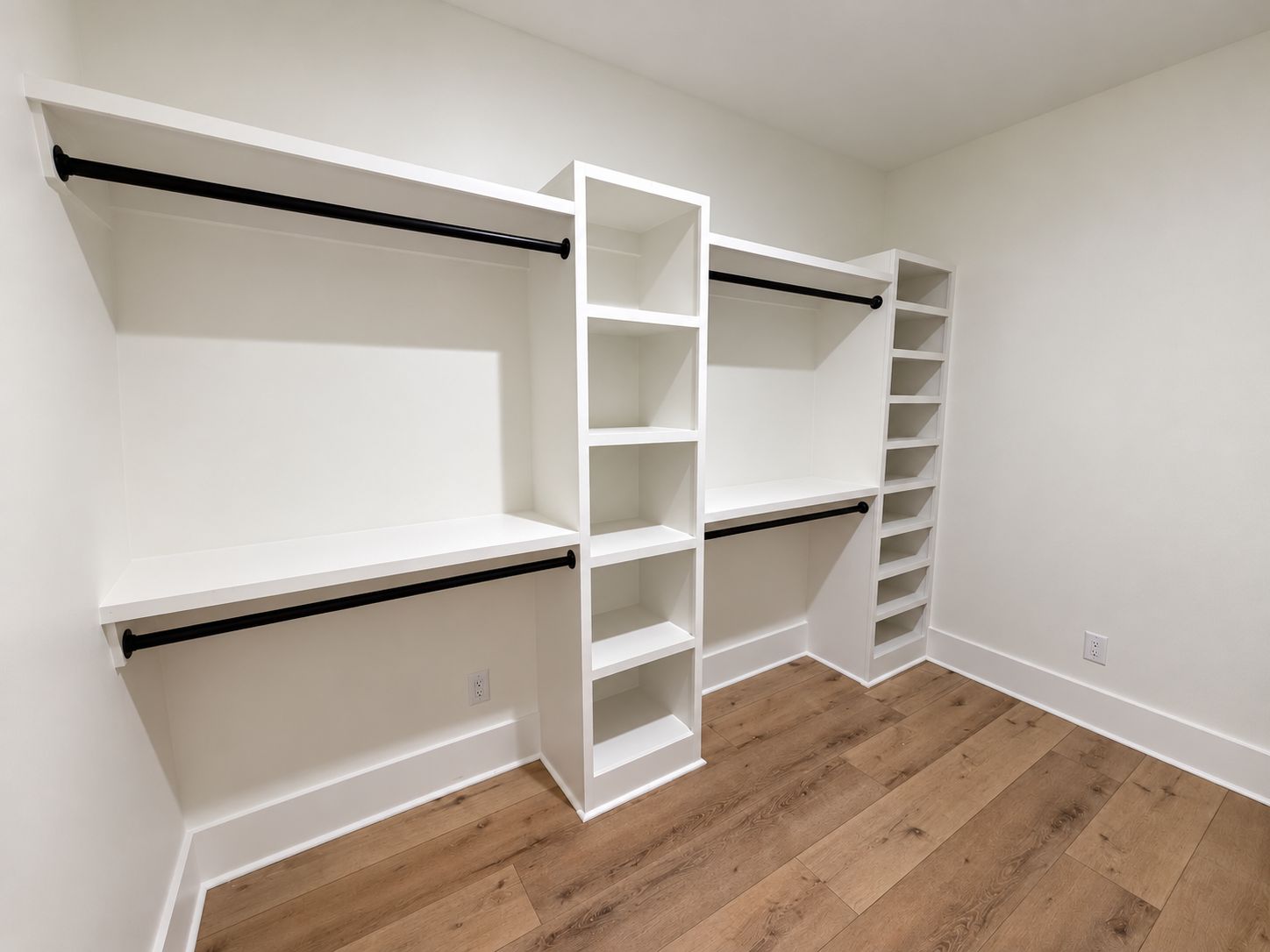 Walk-in closet with white shelving and black hanging rails.