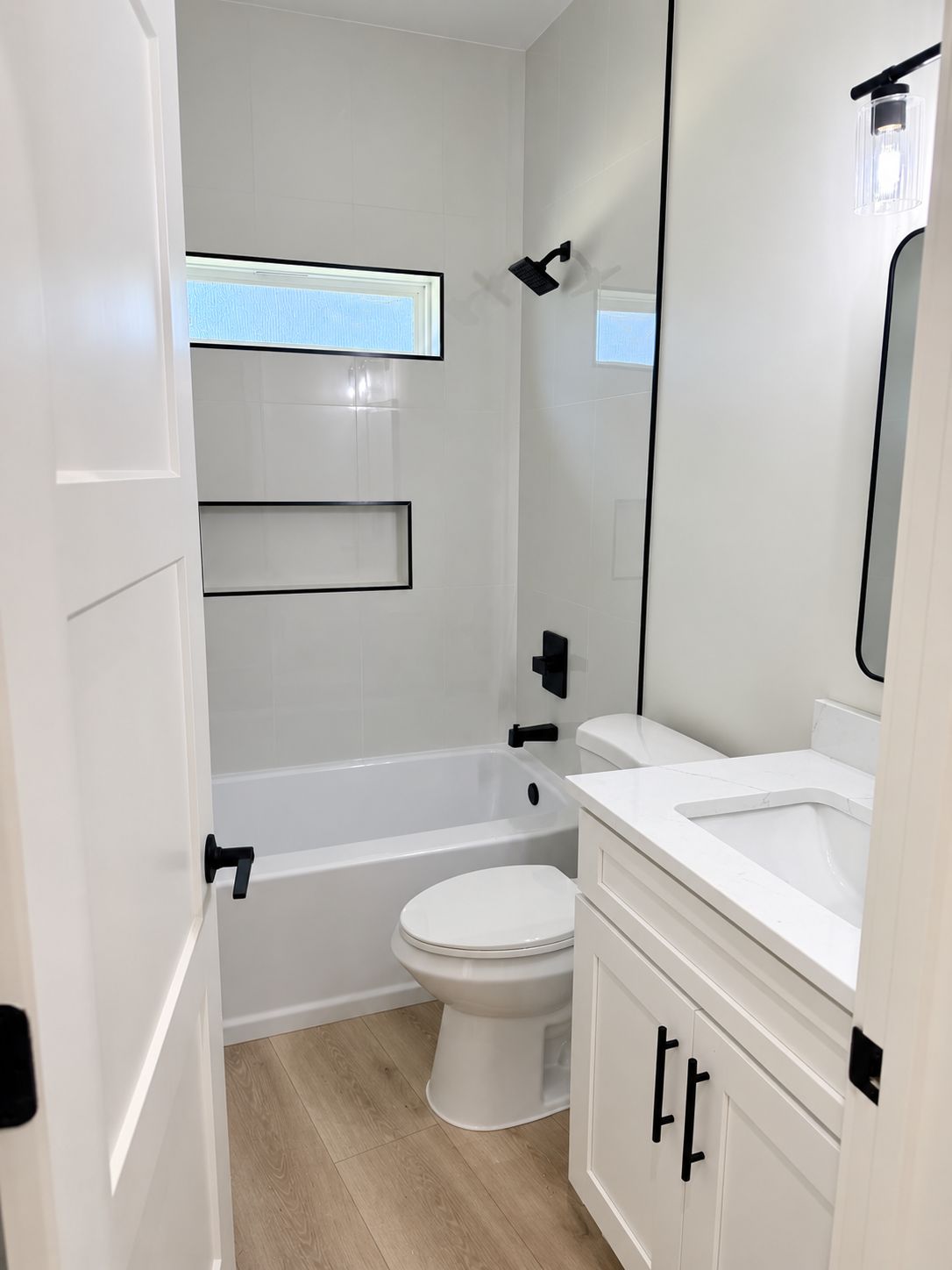 Bathroom with a glass shower, white vanity, and black fixtures.