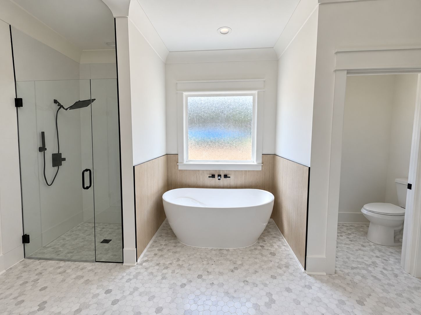 Bathroom with a freestanding tub, glass shower, and patterned tile floor.
