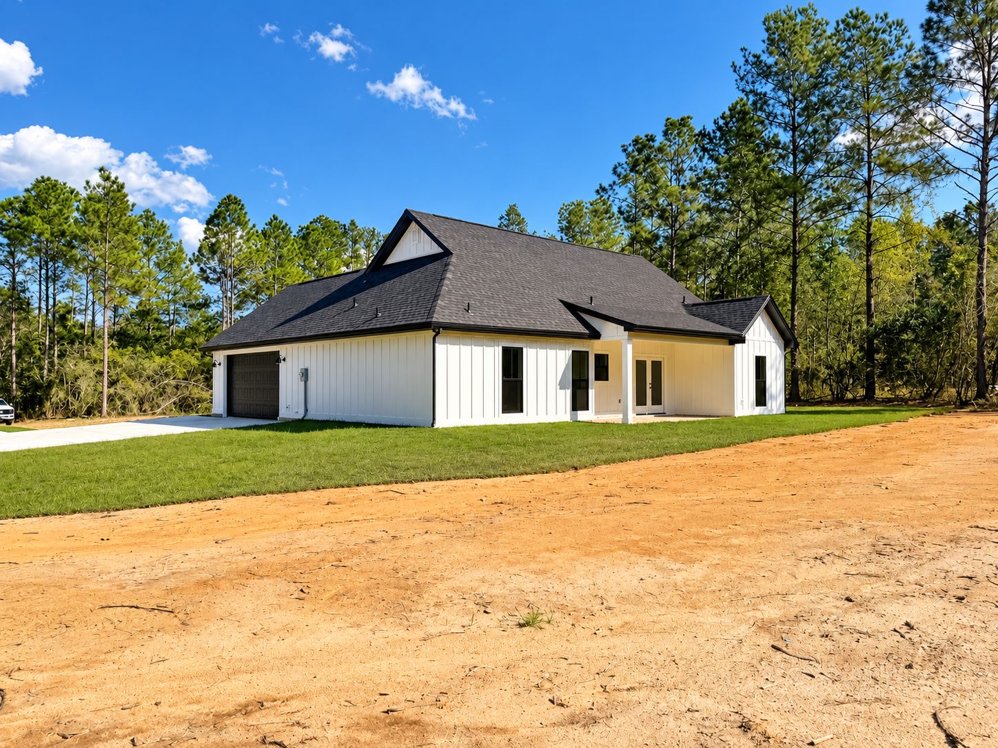 Side and rear exterior view of the white home on a wooded lot.