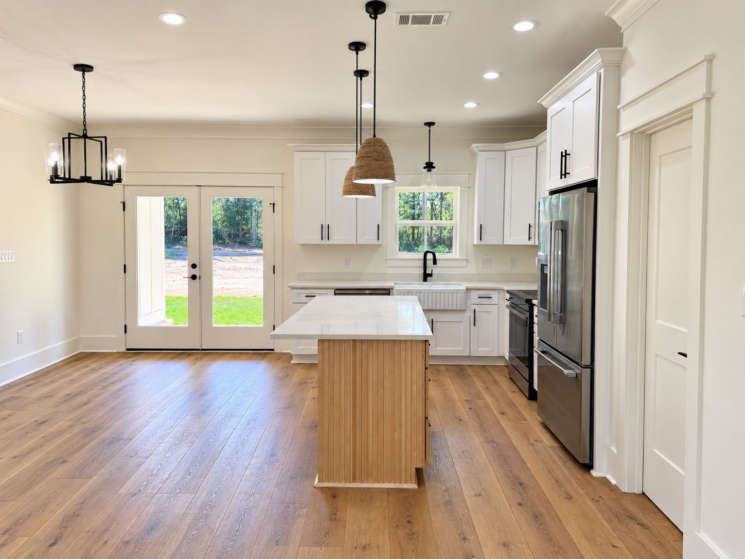 White kitchen with a wood island, pendant lights, and wood-look flooring.