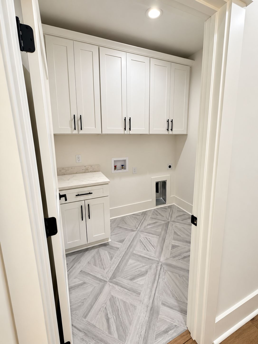 Utility room with white cabinets, a countertop, and patterned tile flooring.