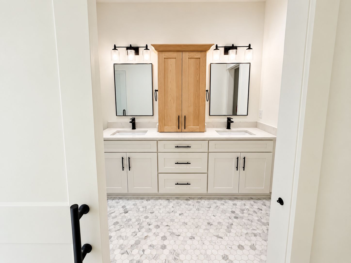 Bathroom with a white double vanity, wood center cabinet, and black-framed mirrors.