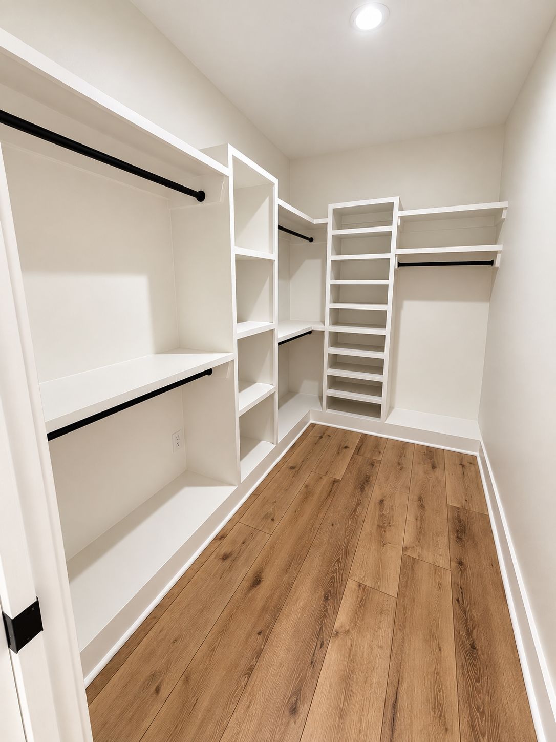 Walk-in closet with white built-in shelving and black hanging rails.