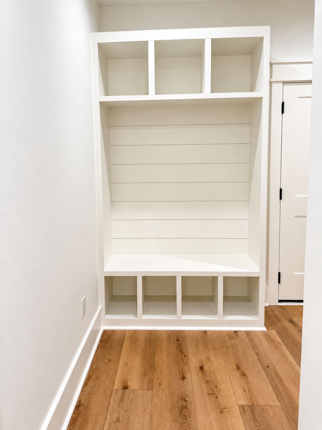 White built-in mudroom bench with upper cubbies and lower storage.