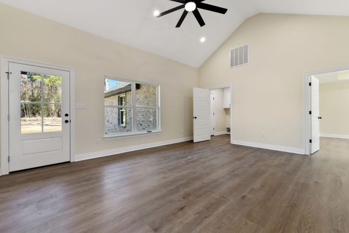 Living room with a vaulted ceiling, black ceiling fan, and wood-look flooring.