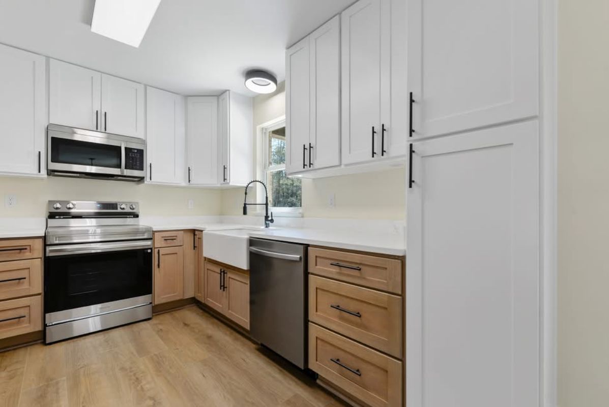 Kitchen with white upper cabinets, wood lower cabinets, and black hardware.
