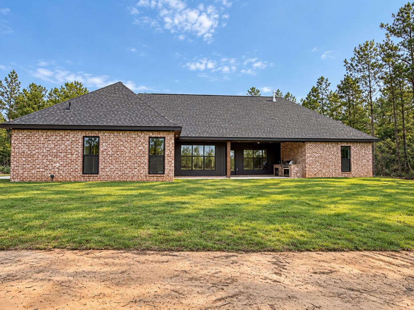 Rear exterior of the completed brick home with a covered patio and lawn.