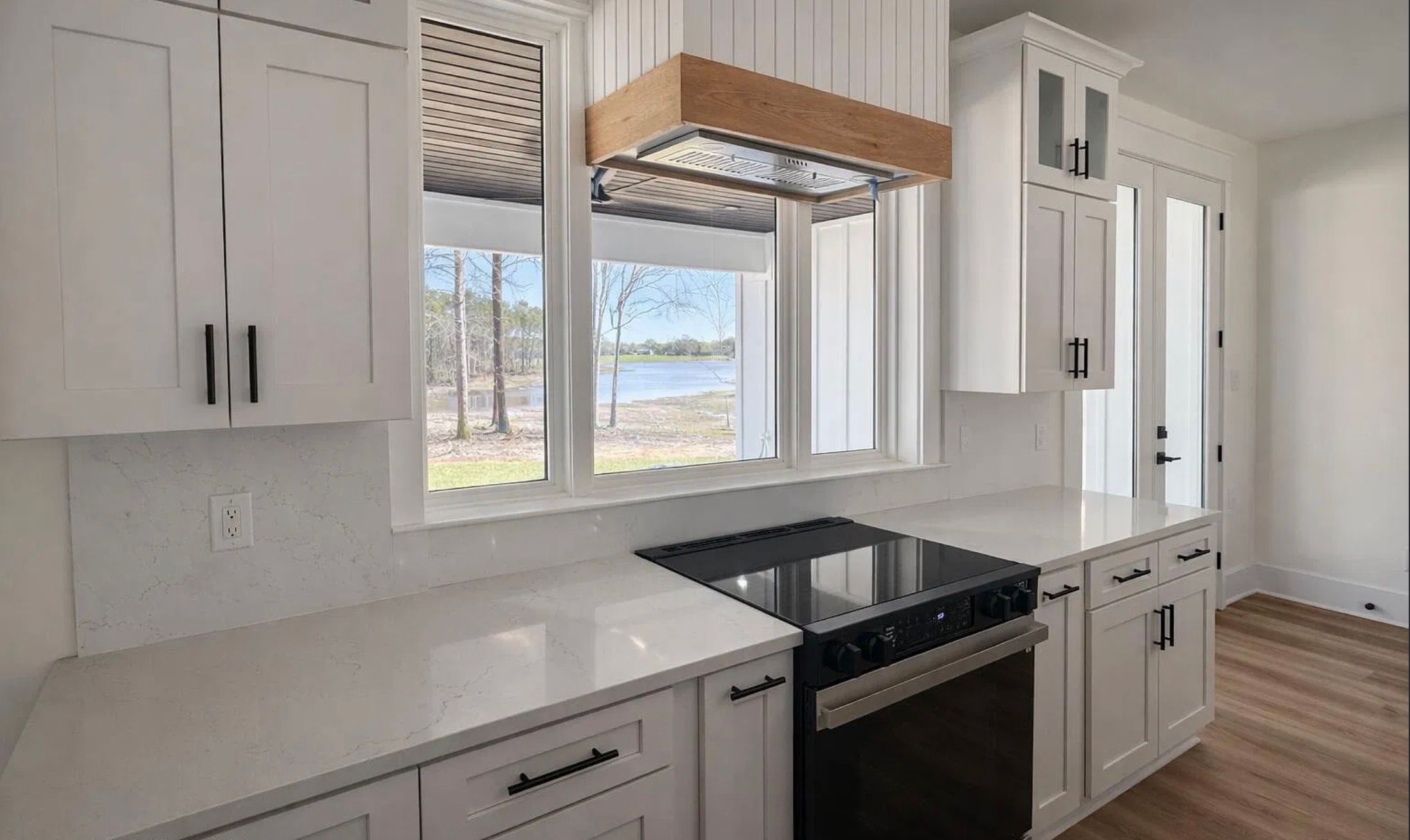 Kitchen counter with a black cooktop, white cabinetry, and a window overlooking the yard.
