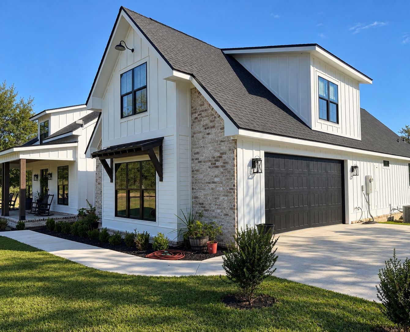 Angled exterior view of the home with a dark garage door, covered front porch, and landscaped walkway.